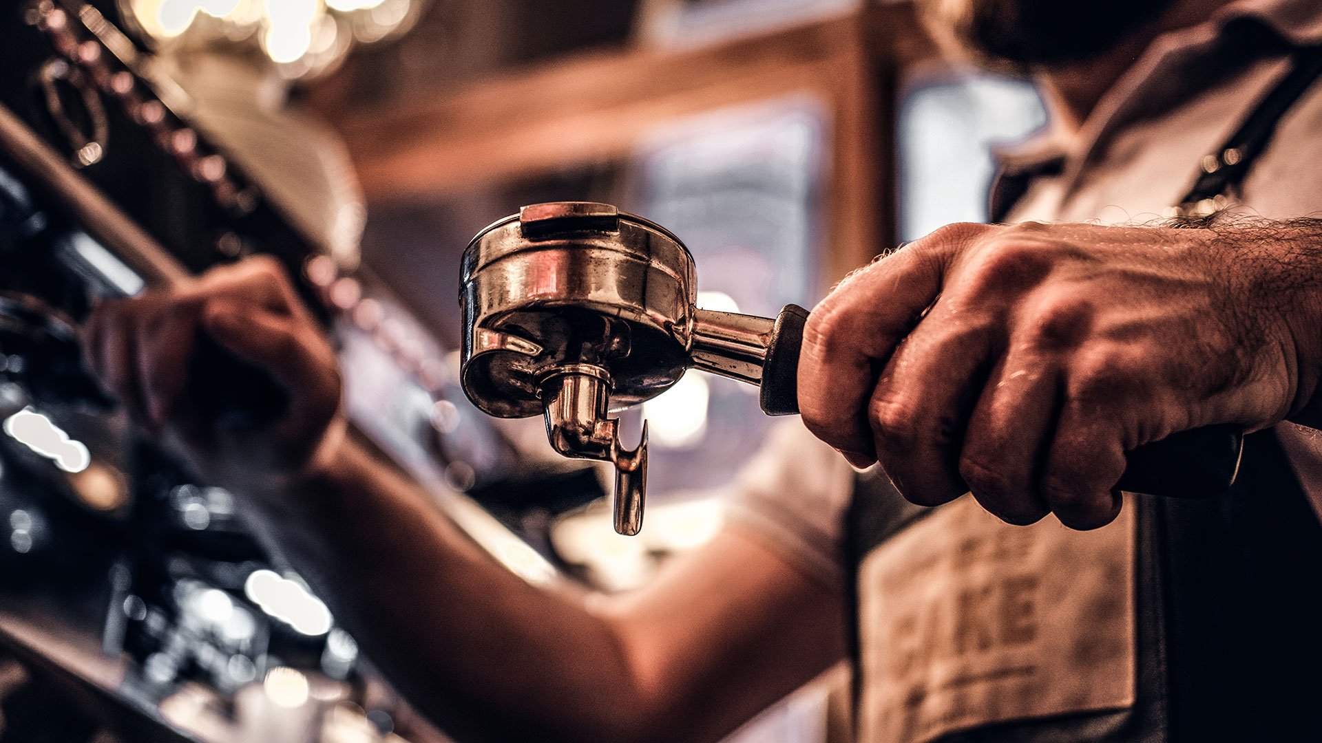 Barista locking a portafilter into a commercial espresso machine